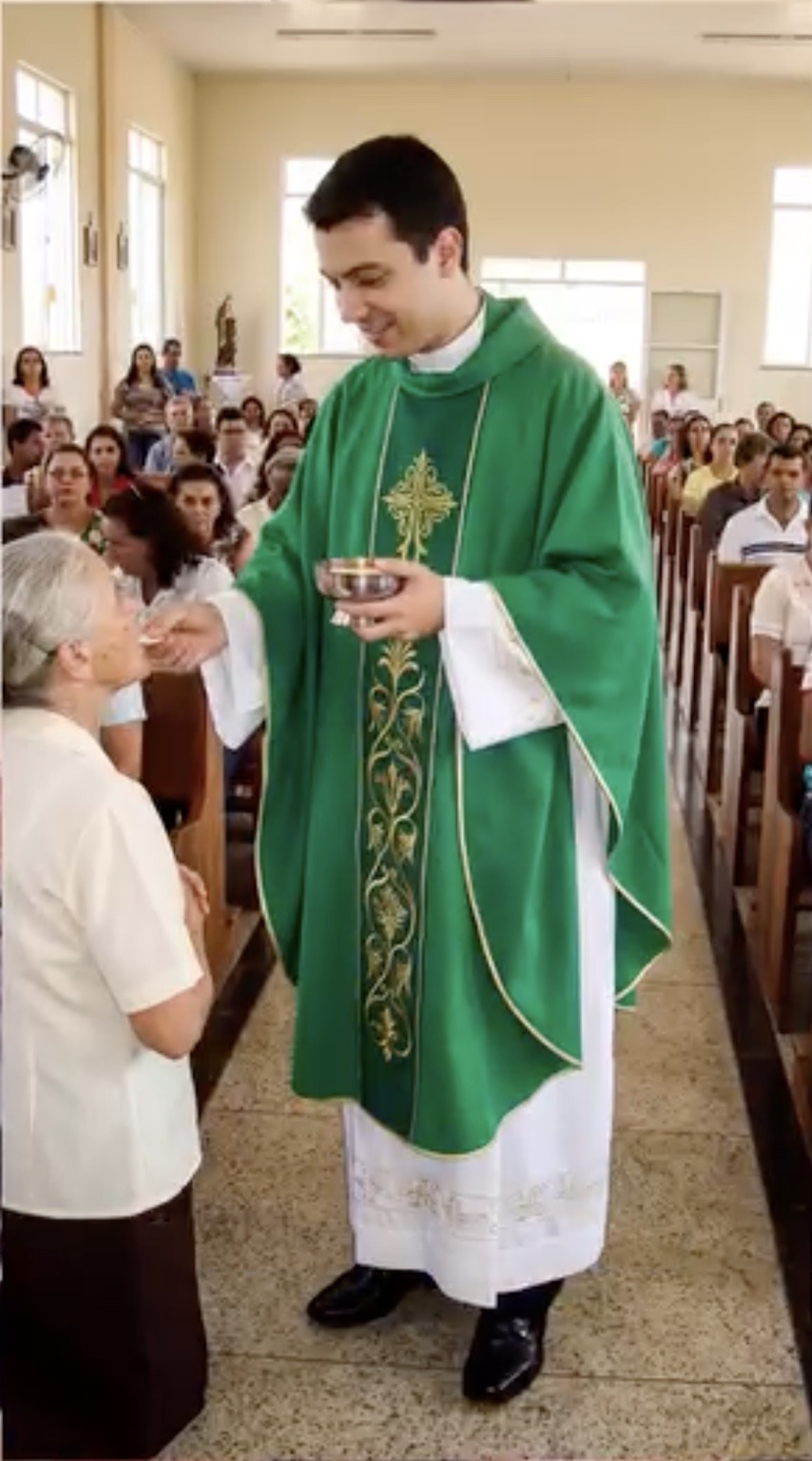 Padre Miguel antes de las amputaciones, de pie y dando la comunión